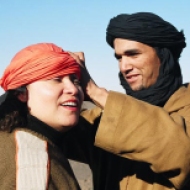 A local Berber guide helps a group member with her head scarf, Sahara Desert, Morocco.