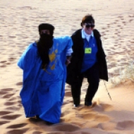 A Blueman helps a Ya'lla traveler climb a dune in the Sahara Desert of Morocco. Tuareg Berbers are known as Bluemen because of their traditional blue scarves and robes.